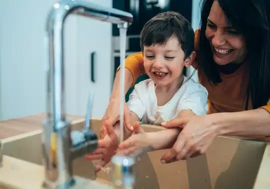 Mom helping son wash hands in kitchen sink in Summerville, SC.