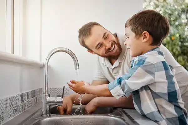 Dad smiling helping son wash his hands in Summerville, SC.
