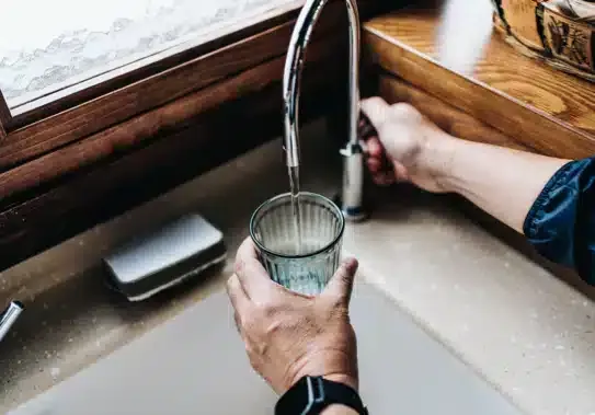 Hands filling cup with water from kitchen sink in Summerville, SC.