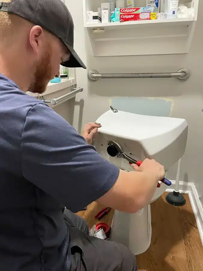 Kinsmen plumber repairing a toilet in a Summerville, SC bathroom using professional tools